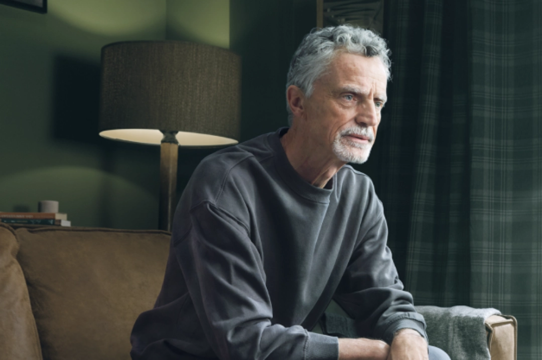 A concerned older man sitting on a couch